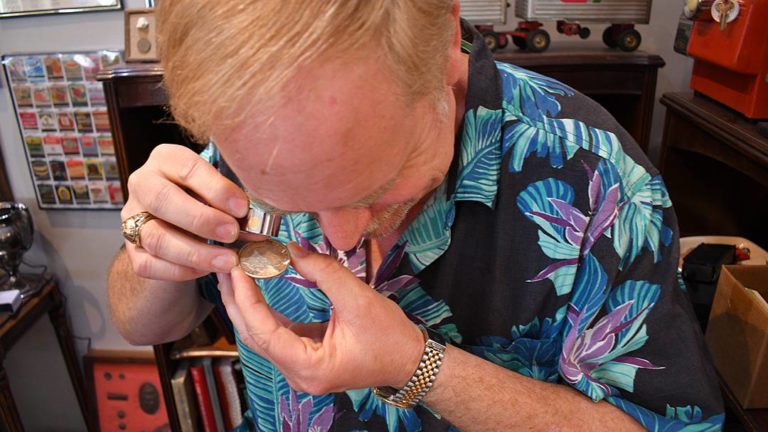John Zalesny, owner of Pismo Beach Coins Etc Gallery, evaluates a collectible coin